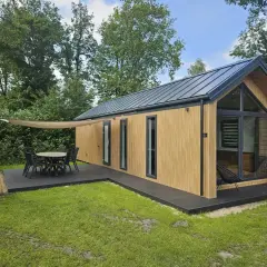 Nowoczesny dom 35m2 z drewnianą elewacją, tarasem i meblami ogrodowymi. Idealne miejsce na wypoczynek.