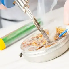 Ręce lutują przewód. W tle widać topnik w tubce.