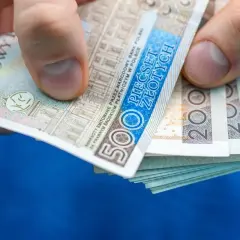 Dłoń trzyma stos banknotów 500 zł i 200 zł. Może to być zapłata za rachunek, np. taryfa urzędowa Energa.