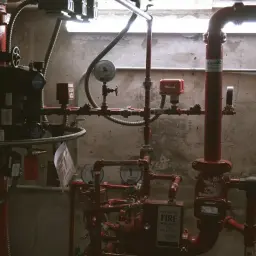 Skomplikowana instalacja co z czerwonymi rurami, manometrami i zaworami, w tym system przeciwpożarowy Viking.