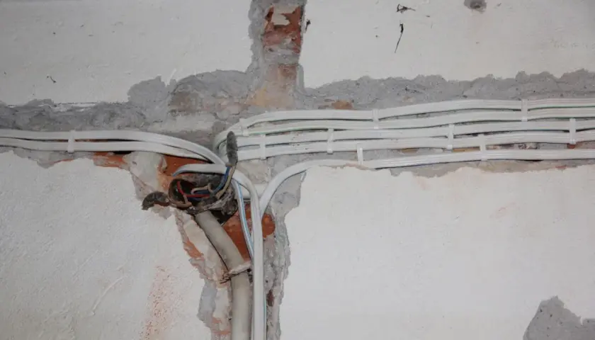 Nowe przewody elektryczne w ścianie, przygotowanie do wymiany instalacji elektrycznej.