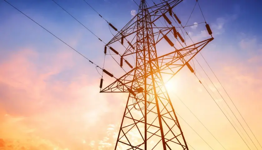 Słupy energetyczne na tle zachodzącego słońca. Zastanawiasz się, ile wynosi odszkodowanie za słupy energetyczne na działce?