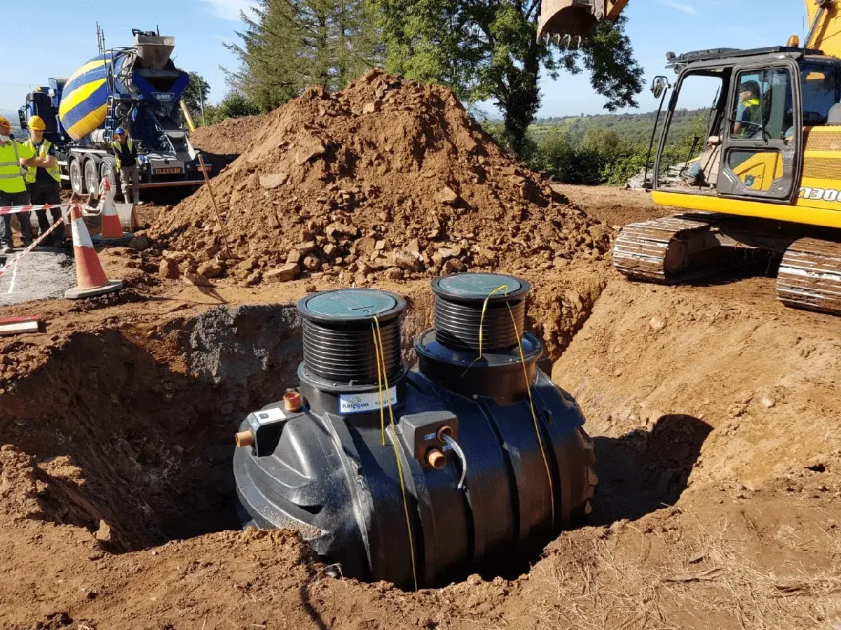 Instalacja przydomowej oczyszczalni ścieków. Koparka i betoniarka na budowie. Sprawdź przydomowa oczyszczalnia ścieków cena.