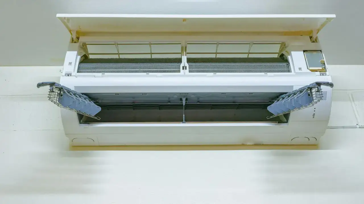 Otwarta klimatyzacja z widocznymi filtrami i żaluzjami. Zastanawiasz się, ile kosztuje odgrzybianie klimatyzacji?