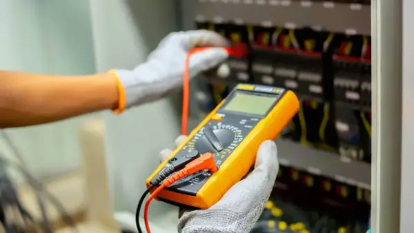 Elektryk z multimetrem wykonuje pomiary elektryczne. Sprawdź nasz cennik usług.